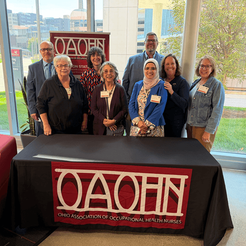 Group of poeple standing behind a table with an OAOHN Ohio Association of Occupational Health Nurses banner