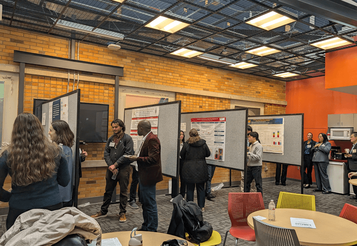 people gathered around poster boards during a conference poster session