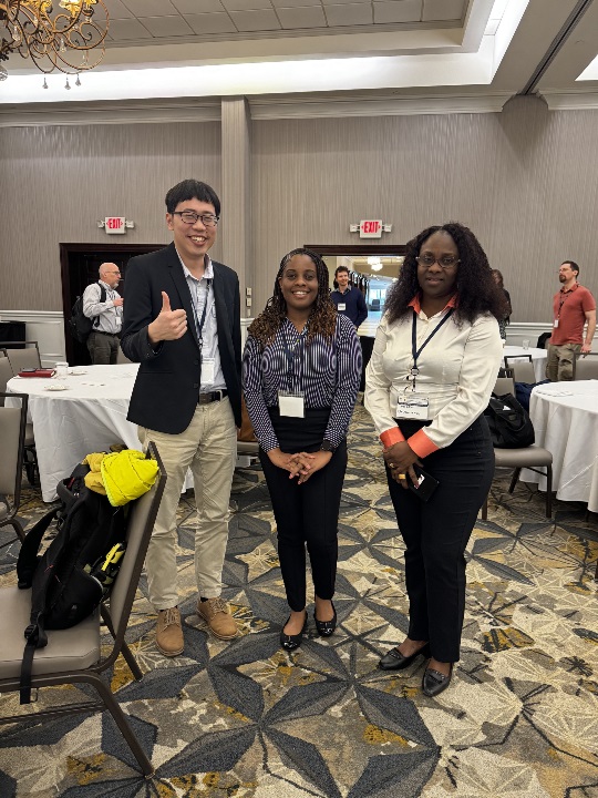 Three people standing together in a hotel conference room