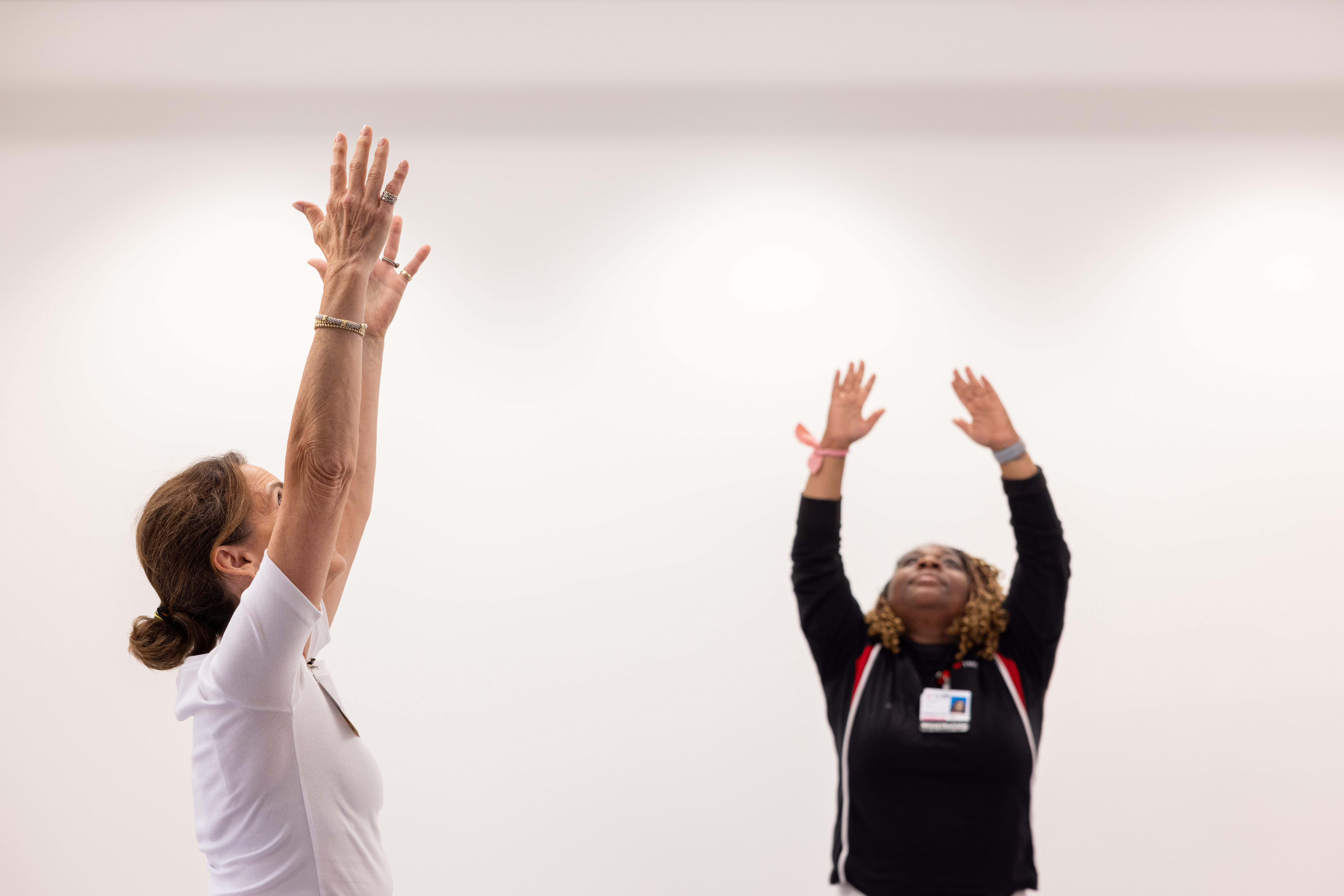 two people performing yoga reaching hands up