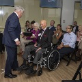 A speaker hands award to a seated participant surrounded by other people clapping