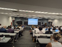 A picture of an auditorium with people watching a presentation projected on a screen.